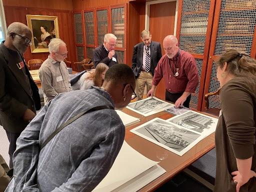 Several people examine prints and other collection items on a table in the LVA Special Collections reading room.