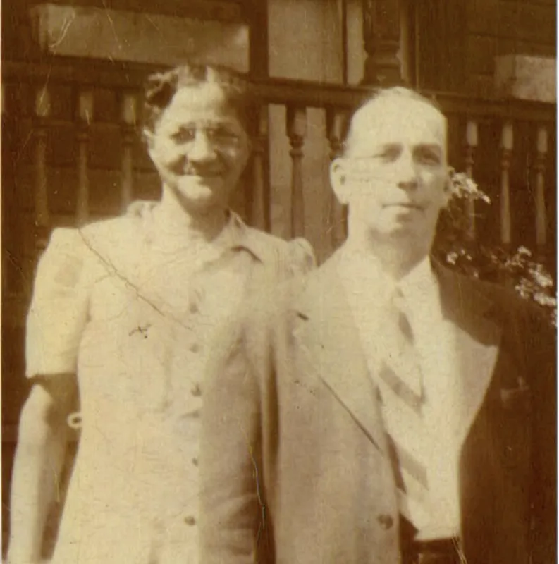 Photograph of a man ( William Lipscomb, b. 1886) and a woman (Pinkie Jeffries Lipscomb, b. ca. 1888) standing in front of a house's front porch.