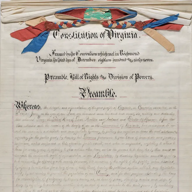 Image shows the front page of the 1868 Constitution for the Commonwealth of Virginia. Handwritten, the document is on multiple pieces of paper, which is tied together at the top with a selection of colorful ribbons.